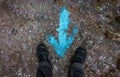 Woman standing at a blue painted direction arrow on the ground