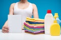Woman standing at board with laundry liquids and clean garments