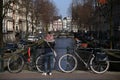 Woman standing on a bridge over Amsterdam canal next to two bicycles Royalty Free Stock Photo