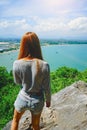 Woman standing on the cliff and see something on the blue sky, blue sea and cloud