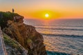 Woman standing on cliff and watching Sunset at Atlantic ocean coast, Portugal