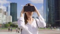 Woman standing in downtown business district using virtual reality glasses. Skyscrapers on background