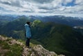 woman standing at the edge of a cliff overlooking high mountains. woman looking out over an idyllic mountain scene Royalty Free Stock Photo