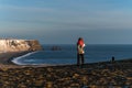 A woman standing on the edge of mountain top, looking at the landscapes of Black Beach Reynisfjara Beach in Iceland