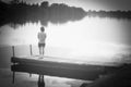 Woman standing at the edge of the pier watching the flow of the lake.