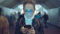 Woman standing in the entrance of a subway station using a smartphone