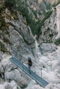 Woman standing on footbridge over mountain torrent, looking at landscape view