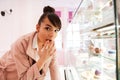 Woman standing in front of the glass showcase with pastries indoors Royalty Free Stock Photo