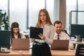 Woman is standing in front of her colleagues. Business people in formal clothes are working in the office together Royalty Free Stock Photo