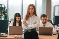 Woman is standing in front of her colleagues. Business people in formal clothes are working in the office together Royalty Free Stock Photo