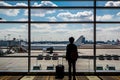 A woman is standing in front of a large airport window Royalty Free Stock Photo