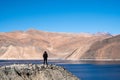 A woman standing in front of Pangong lake with mountains view and blue sky Royalty Free Stock Photo