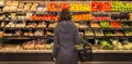 Woman standing in front of a row of produce in a grocery store. Royalty Free Stock Photo