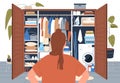 Woman standing in front of tidy wardrobe after decluttering. Back of person looking at open closet with arranged clothes