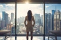 Woman Standing in Front of Window, Looking Out at City Royalty Free Stock Photo