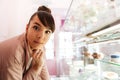 Woman standing at the glass showcase with patries inside cafe