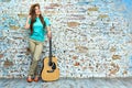 Woman standing with guitar against grunge wall Royalty Free Stock Photo