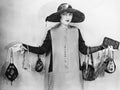 Woman standing with her arms apart wearing handbags