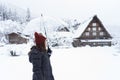 Woman standing and holding transparent umbrella in the winter and snow is falling at Shirakawago village, Japan. Royalty Free Stock Photo