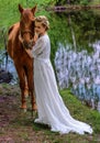 Woman standing with horse near lake and touching horse face with her forehead