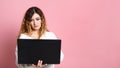 Woman standing isolated on a pink background using a laptop computer. With a place for a copy space Royalty Free Stock Photo