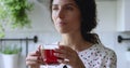 Woman standing in kitchen drinking hot fresh brewed black tea