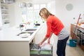 Woman Standing In Kitchen Emptying Waste Bin