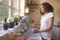 Woman Standing At Kitchen Sink Washing Up