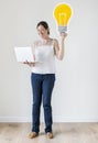Woman standing with a laptop and light bulb Royalty Free Stock Photo