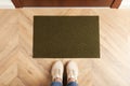 Woman standing near door mat on wooden floor in hall, top view Royalty Free Stock Photo