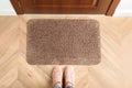 Woman standing near door mat on wooden floor in hall, top view Royalty Free Stock Photo