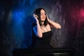 Woman standing near the mixing table and computer wearing headphones, producing electronic music Royalty Free Stock Photo