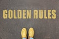 Woman standing near phrase GOLDEN RULES on asphalt