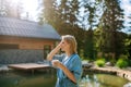 Woman, standing near private lake, relaxing, enjoying cup of morning coffee on summer vacation in mountains. Royalty Free Stock Photo