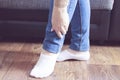 Woman standing near sofa, holding her ankle injury, feeling pain. Health care and medical concept. High quality photo Royalty Free Stock Photo