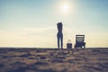 Woman standing near sun lounger and taking off her clother. Beach at sunset