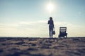 Woman standing near sun lounger and taking off her clother. Beach at sunset