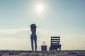 Woman standing near sun lounger and taking off her clother. Beach at sunset