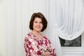 Woman is standing near tulle white curtains