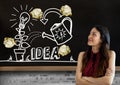 Woman standing next to light bulb and ideas drawings garden with crumpled paper balls in front of b Royalty Free Stock Photo