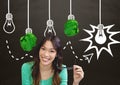 Woman standing next to light bulbs with crumpled paper balls in front of blackboard Royalty Free Stock Photo