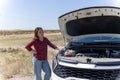 Woman standing next to open car hood, examining engine Royalty Free Stock Photo