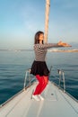 Woman standing on the nose of the yacht at a sunny summer day, breeze developing hair, beautiful sea on background Royalty Free Stock Photo