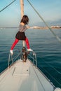 Woman standing on the nose of the yacht at a sunny summer day, breeze developing hair, beautiful sea on background Royalty Free Stock Photo