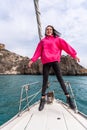 Woman standing on the nose of the yacht at a sunny summer day, breeze developing hair, beautiful sea on background Royalty Free Stock Photo