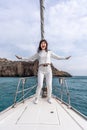 Woman standing on the nose of the yacht at a sunny summer day, breeze developing hair, beautiful sea on background Royalty Free Stock Photo