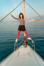 Woman standing on the nose of the yacht at a sunny summer day, breeze developing hair, beautiful sea on background Royalty Free Stock Photo