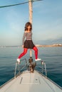 Woman standing on the nose of the yacht at a sunny summer day, breeze developing hair, beautiful sea on background Royalty Free Stock Photo