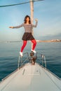 Woman standing on the nose of the yacht at a sunny summer day, breeze developing hair, beautiful sea on background Royalty Free Stock Photo