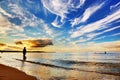 Woman standing in ocean. Dramatic sunset sky